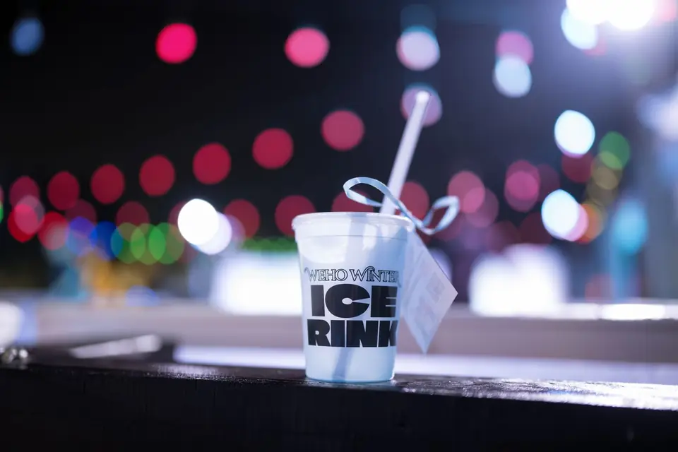 A WeHo Winter Ice Rink cup against holiday lights
